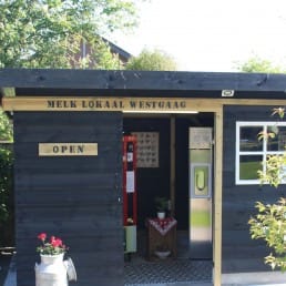 zwart houten gebouw met daar in een melktap en een automaat met kaas en eieren bij Melk Lokaal Westgaag in Midden-Delfland