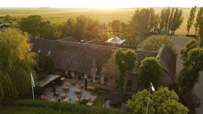 luchtfoto van de boerderij waarin Brasserie Oostgaag gevestigd is midden tussen de weilanden en in de polder van Midden-Delfland