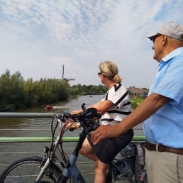 man en vrouw met fiets ebike die poseren op de Trambrug in Schipluiden in Midden-Delfland tijdens een fietstocht door de polders uitkijkend over de Vlaardingsevaart