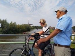 man en vrouw met fiets ebike die poseren op de Trambrug in Schipluiden in Midden-Delfland tijdens een fietstocht door de polders uitkijkend over de Vlaardingsevaart
