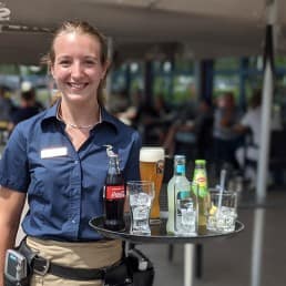 jonge dame in blauw shirt die bedient op het terras van Brasserie Delfland van Golfbaan Delfland in Midden-Delfland