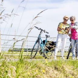 twee dames met ebikes kijken op een routekaart tijdens een fietstocht in de polder in de zomer in Midden-Delfland