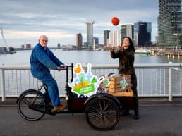 Boer Arie van den Berg met Natascha Hokke van Natuurmonumenten op de Erasmusbrug met een bakfiets vol streekproducten uit Midden-Delfland midden in Rotterdam