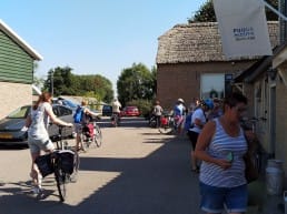 deelnemers aan de fietsroute van Fietsen voor m'n eten staan met de fiets op het boerenerf buiten de winkel van Zuivelboerderij van Winden in Midden-Delfland