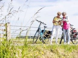 twee dames met ebikes kijken op een routekaart tijdens een fietstocht in de polder in de zomer in Midden-Delfland