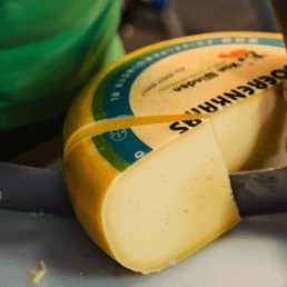 groot stuk kaas van Kaas- en zuivelboerderij van Winden waar een stuk kaas van afgesneden wordt