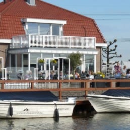 foto van het terras van eetcafe de bonte haas en de huursloepen die voor het terras in het water liggen in het Westland